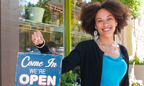 a female business owner holding a welcoming open sign